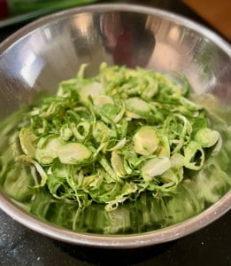 Metal bowl containing trimmed and sliced Brussels Sprouts