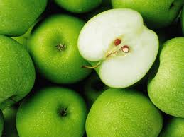Close-up of bright green apples, with one half showing white flesh and seeds inside.