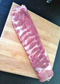 Raw pork tenderloin on a wooden cutting board, ready for trimming or cooking prep.